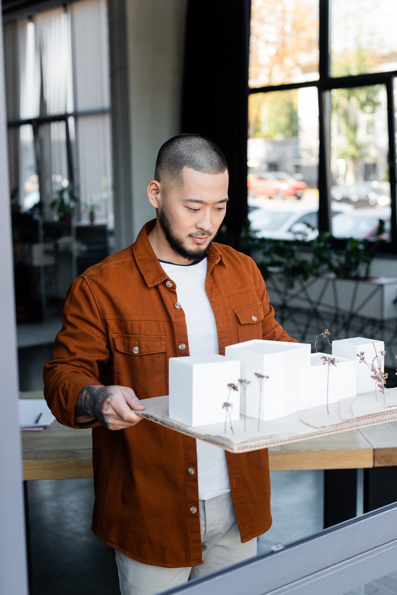 asian architect holding house models while working in architectural design studio